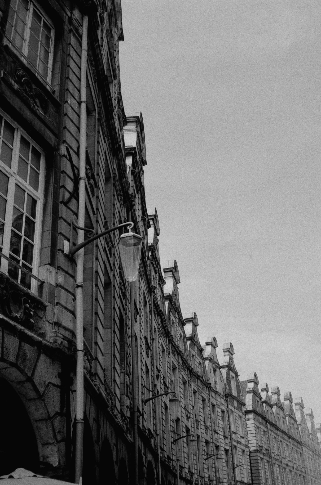 A row of ornate curved gables receding along an old street, with a lantern in the foreground