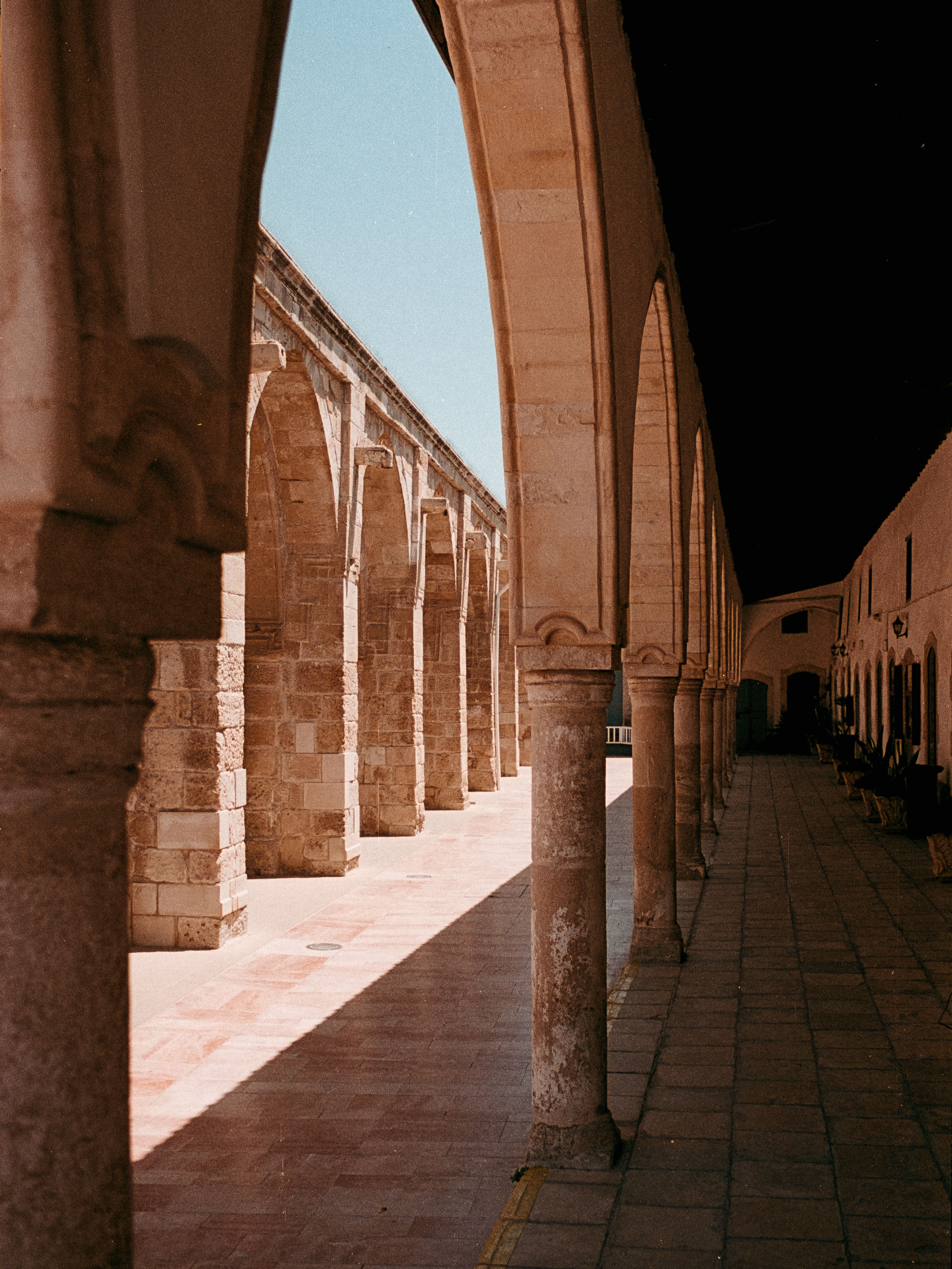 A sunlit stone arcade of pointed arches resting on slender columns